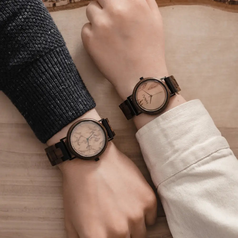 Two matching aava 42mm wooden watches with dark brown frames and straps and light faces with subtle map patterns