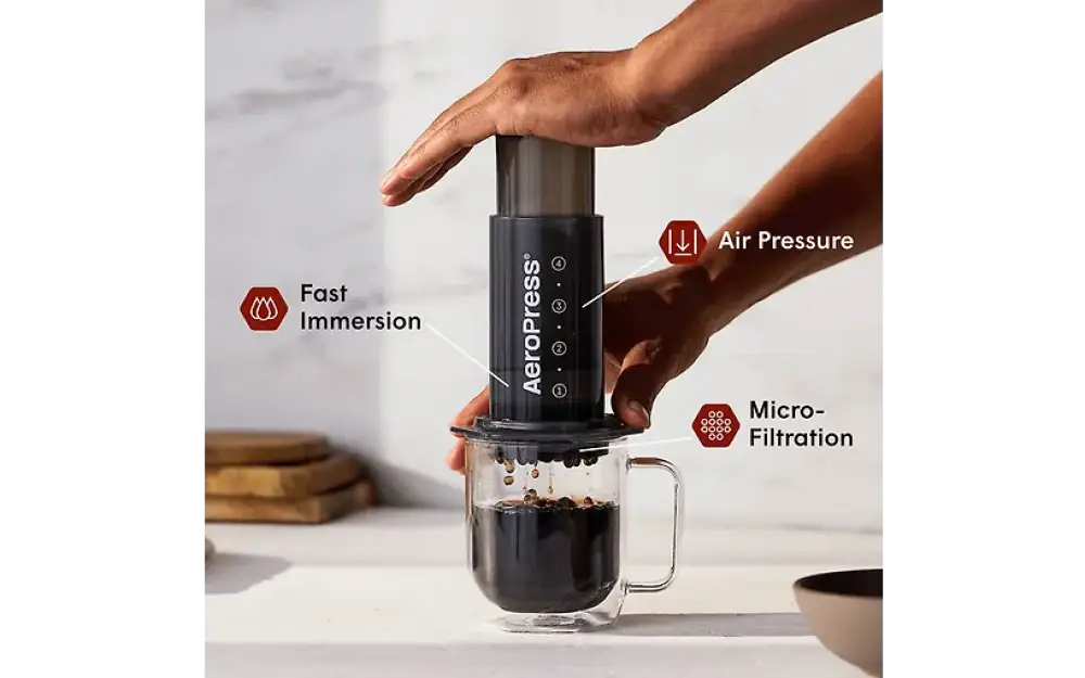 Aerobie aeropress kahvinvalmistuslaite musta läpinäkyvällä lasipohjalla ja sylinterimäisellä mäntärungolla