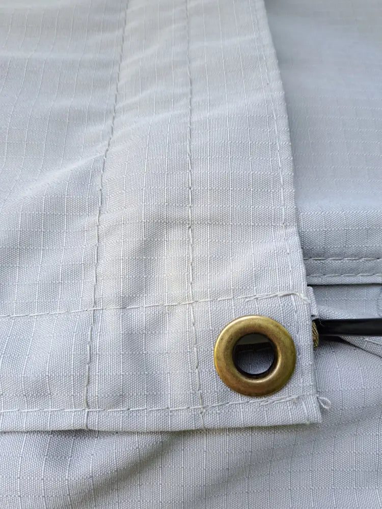 Light gray canvas fabric with a subtle grid pattern and brass-colored metal grommet in auton kattoteltta ilma lyhyt 1.4 harmaa