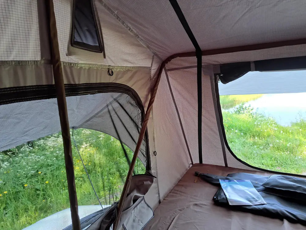 The interior of a beige and black auton kattoteltta ilma pitkä 1.4 harmaa pop-up teltta with mesh windows wooden poles and brown sleeping mat