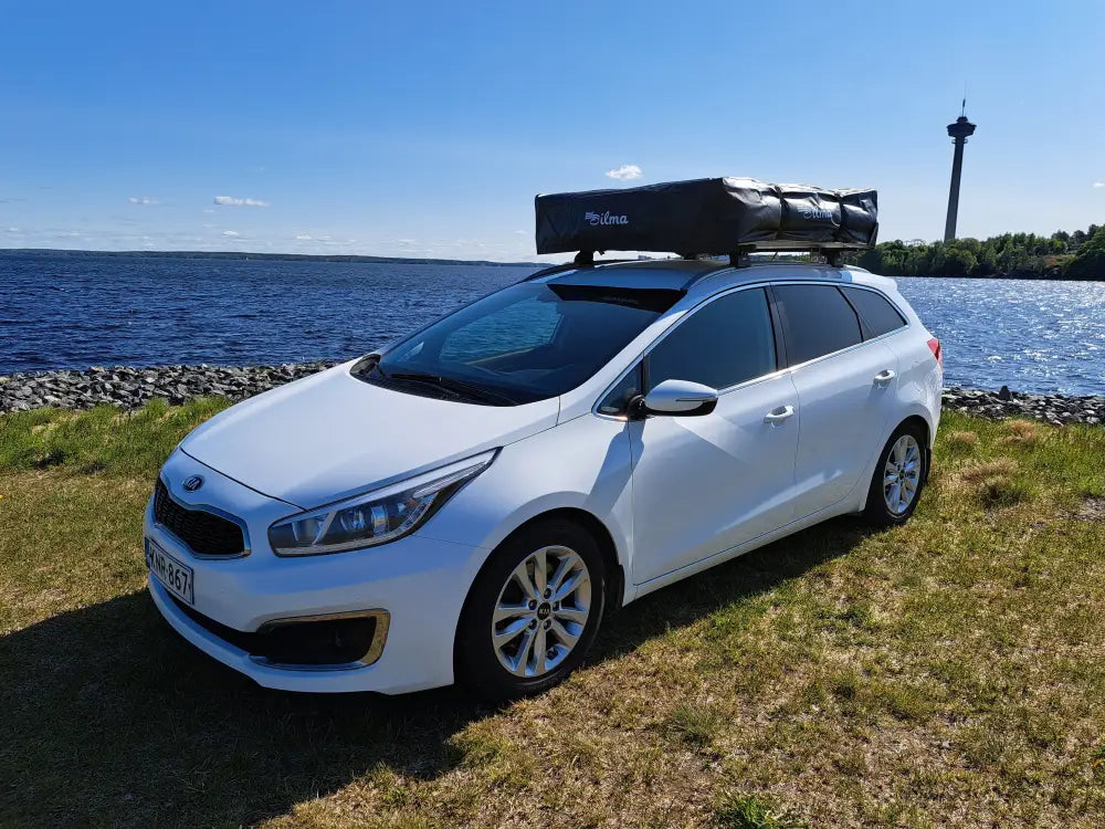 Valkoinen kia ceed farmariauto mustalla kattoboksilla auton kattoteltta ilma pitkä 1.4 harmaa takaa kuvatuna