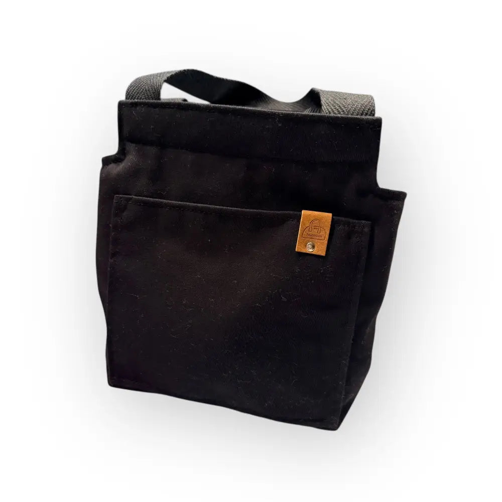 Black canvas eväskassi festival tote bag with sturdy handles and tan leather patch on front pocket