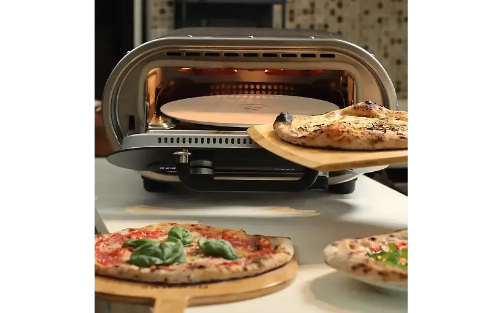 Silveri ja musta sähkökäyttöinen evolve pizzauuni pyöreällä paistokivellä ja tuore pizza uunissa