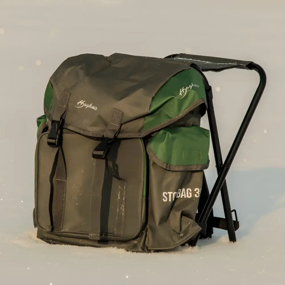 Green and olive utility backpack with black metal folding chair frame integrated in haghus stol bag reppujakkara 35l