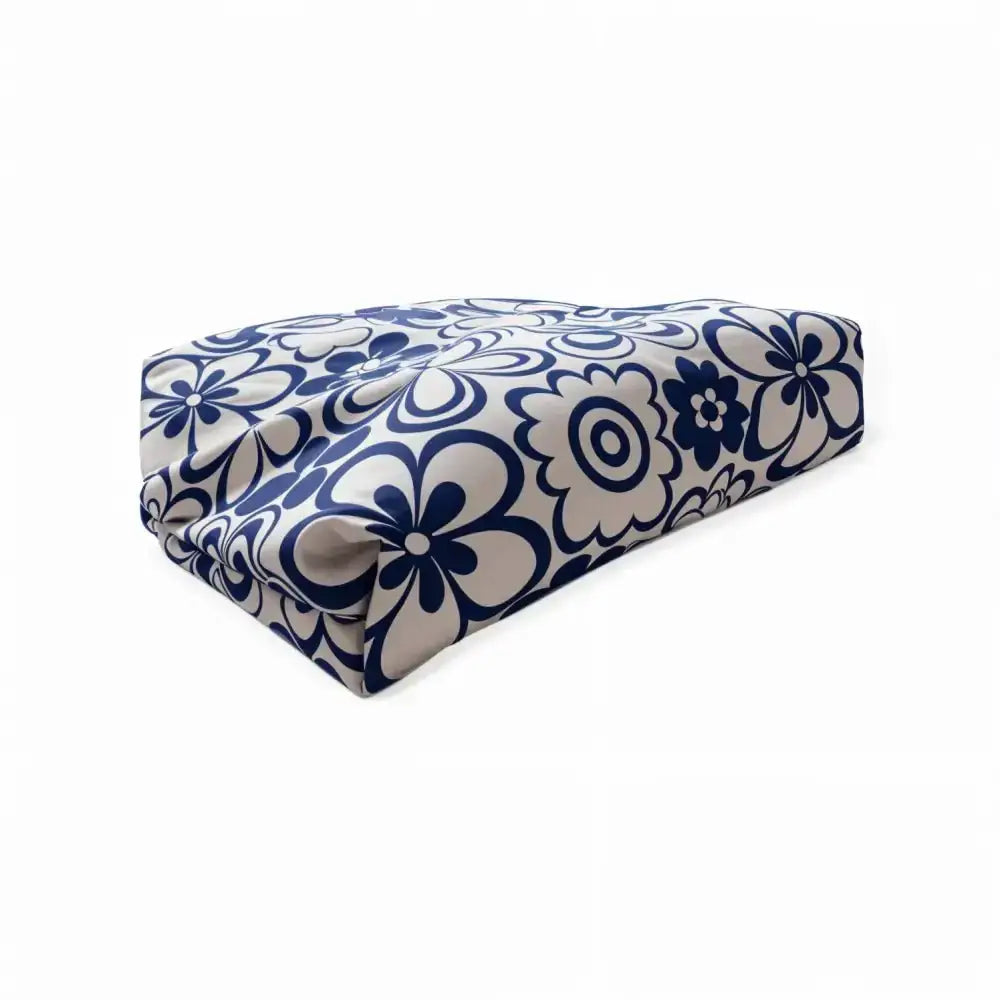 A rectangular meikkilaukku flower cushion upholstered in bold navy blue and cream floral fabric