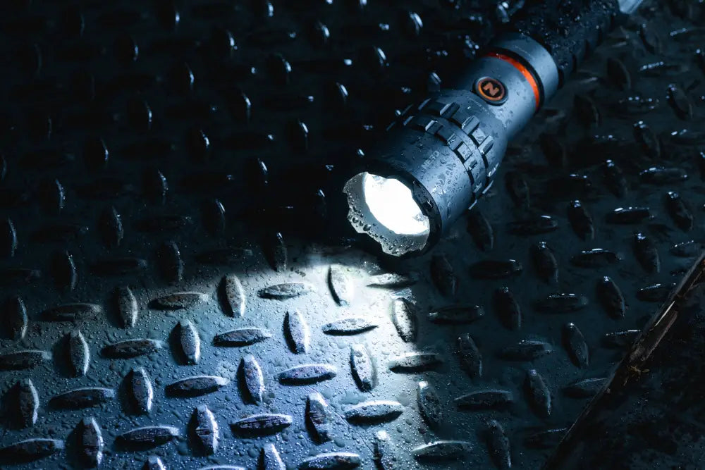 Black tactical flashlight slyde king 4k with textured grip orange accent ring emitting bright white beam